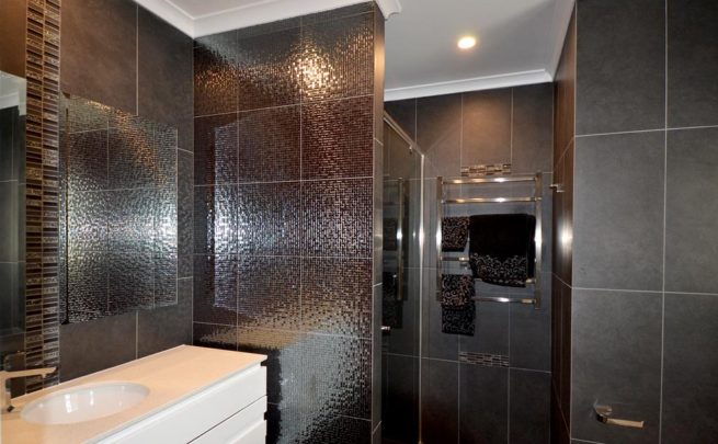 Bathroom with dark wall tiles, shiny around the vanity