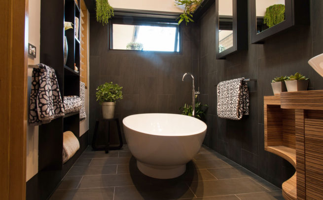 Slate-tiled bathroom with a freestanding bath, plants and lots of light