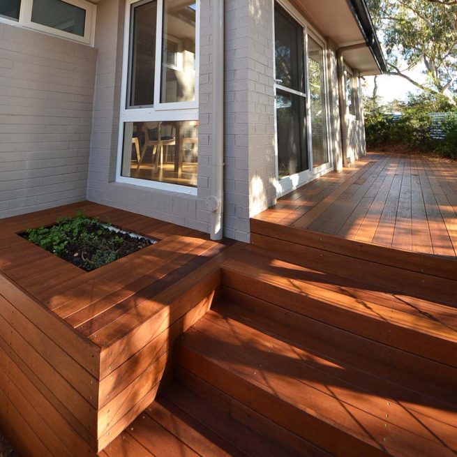 Timber-framed planter box next to steps leading to a deck along the side of a hose