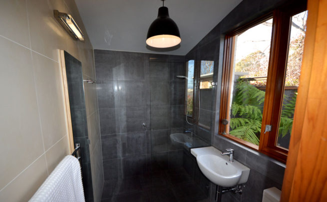 Bathroom with grey slate tiles, timber framed window