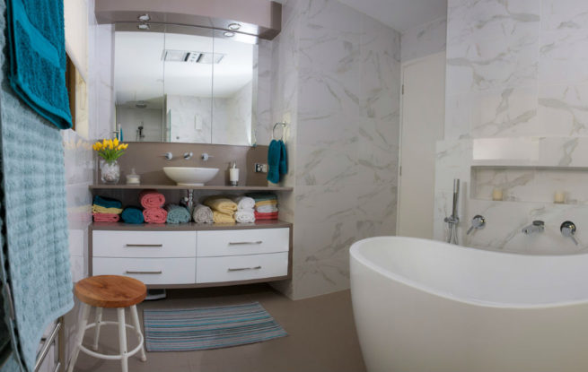 Bathroom showing towels and a stool in front of a vanity unit, with a freestanding bath to the right